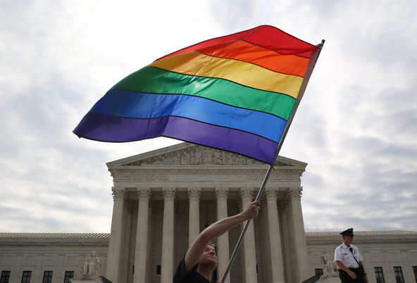 Man waving pride flag in front of Supreme Court building