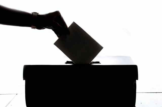 person dropping paper into ballot box