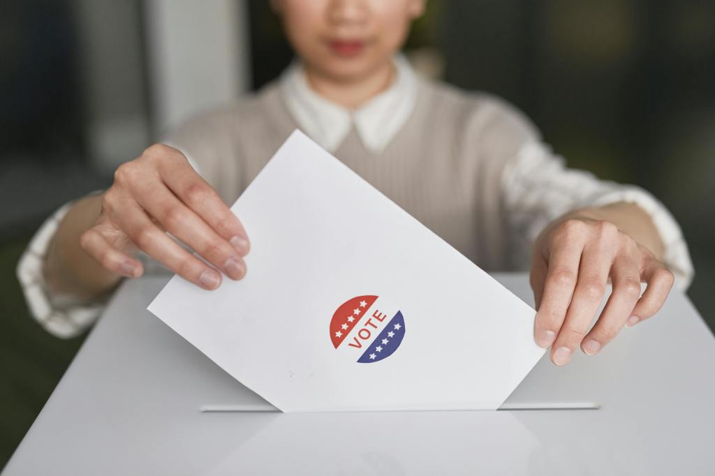 Picture of a woman inserting a ballot into a ballot box. 