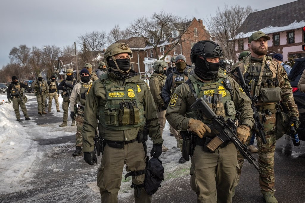 Masked and armed ICE agents patrolling a residential street in Minneapolis. 