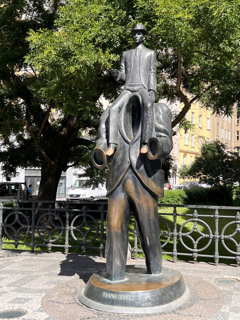 Bronze statue of Franz Kafka on the shoulders of a headless man.